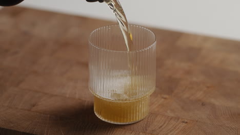 pouring beer from bottle into drinking glass at home in the kitchen