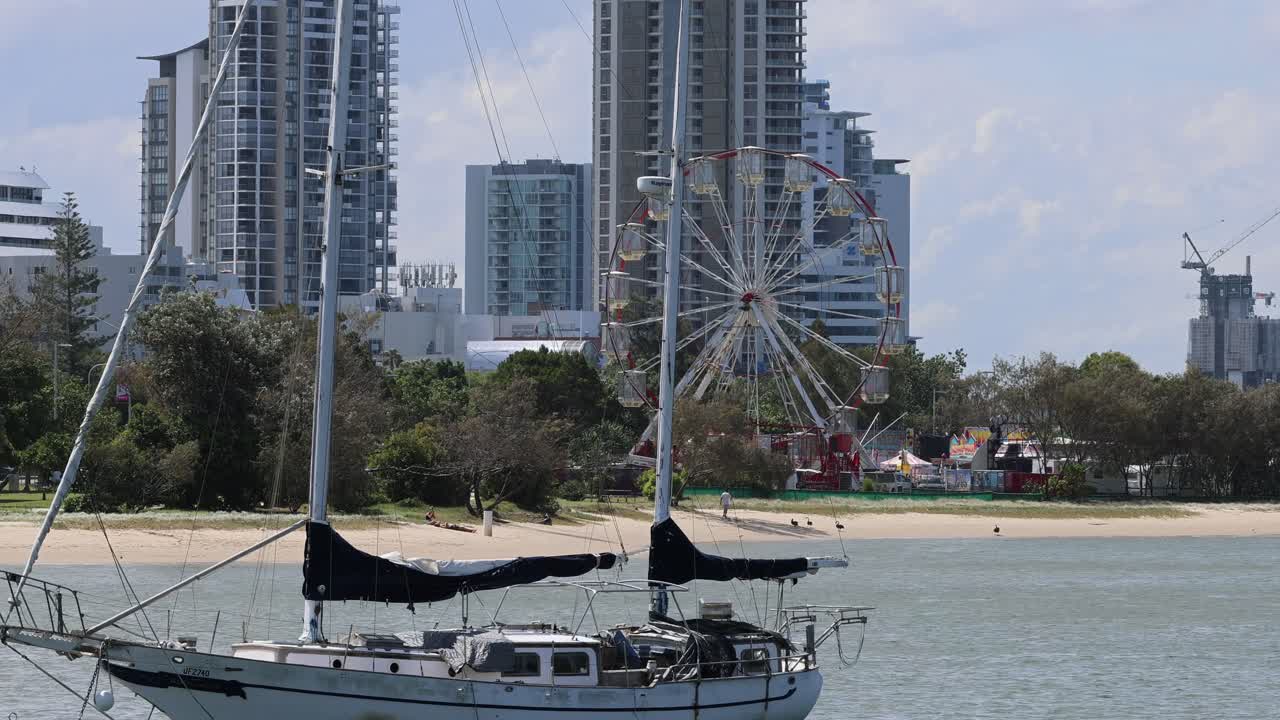 A sailboat moves past a Ferris wheel
