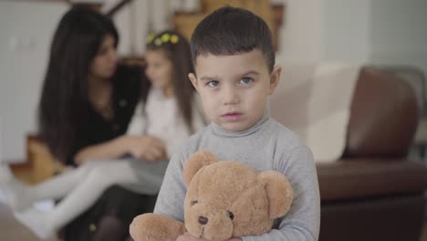 encantador niño de oriente medio con ojos grises y cabello oscuro sosteniendo el oso de peluche y mirando a la cámara