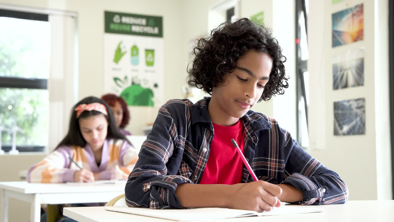 Smiling boy writing in classroom, enjoying learning with multiracial students at school
