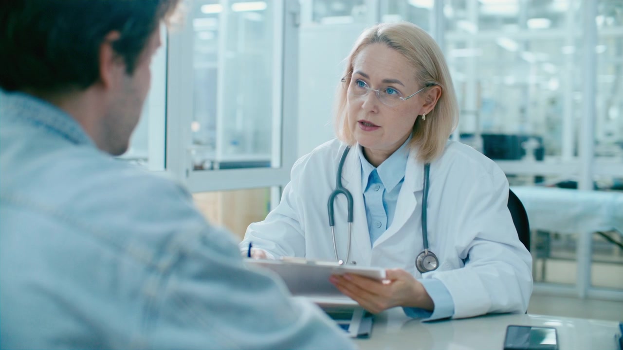 Experienced Female Doctor Reviewing Medical Records and Consulting Patient