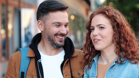 close-up view of caucasian man and redheaded woman talking and walking down the street