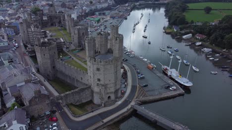 Altes-Caernarfon-Castle-Walisische-Hafenstadt-Luftaufnahme-Mittelalterliches-Wahrzeichen-Am-Wasser-Langsam-Links-Mit-Blick-Auf-Dolly