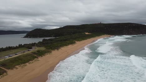 drone flying over beautiful sandy beach revealing a bay on the other side of the peninsula