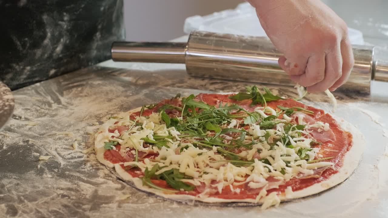 요리사는 피자를 만들고 치즈를 뿌립니다.