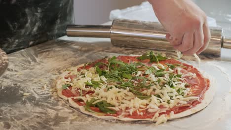 el chef hace la pizza y la salpica con queso
