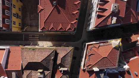 Red-orange-roofs-catch-midday-sunight-providing-shade-below-to-streets-in-Lisbon-Portugal