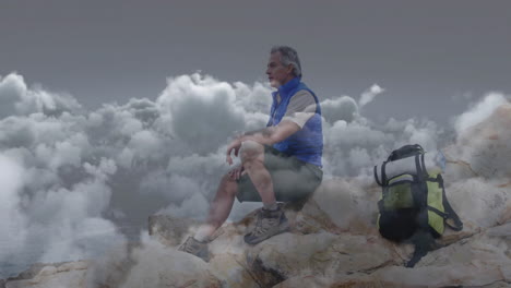 mature male hiker sitting rocky summit above clouds with backpack, showing business chart overlay
