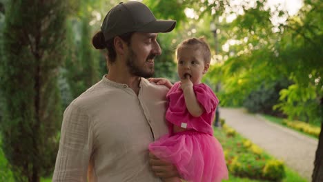 un padre sosteniendo a su linda hija en un parque