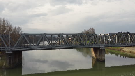 drone flies quickly above the water away from a bridge above the arno river