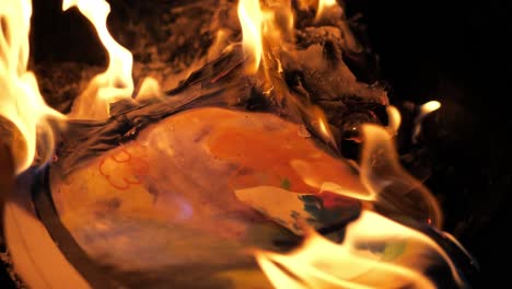 Fire-burning-with-a-kid's-childhood-butterfly-paper-art-project-burning-up-in-a-house-fire-pit-in-4k-60fps