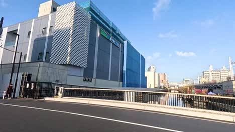a busy tokyo street with modern buildings and vehicles passing by under clear blue skies, captured in dynamic motion
