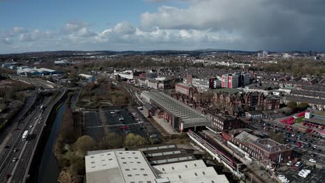 Aerial-footage-of-trains-approaching-Stoke-on-Trent-train-station-in-the-midlands-by-the-canal,-waterside-and-A50-motorway,-the-midway-point-for-commuters-who-travel-north-and-south-through-the-UK