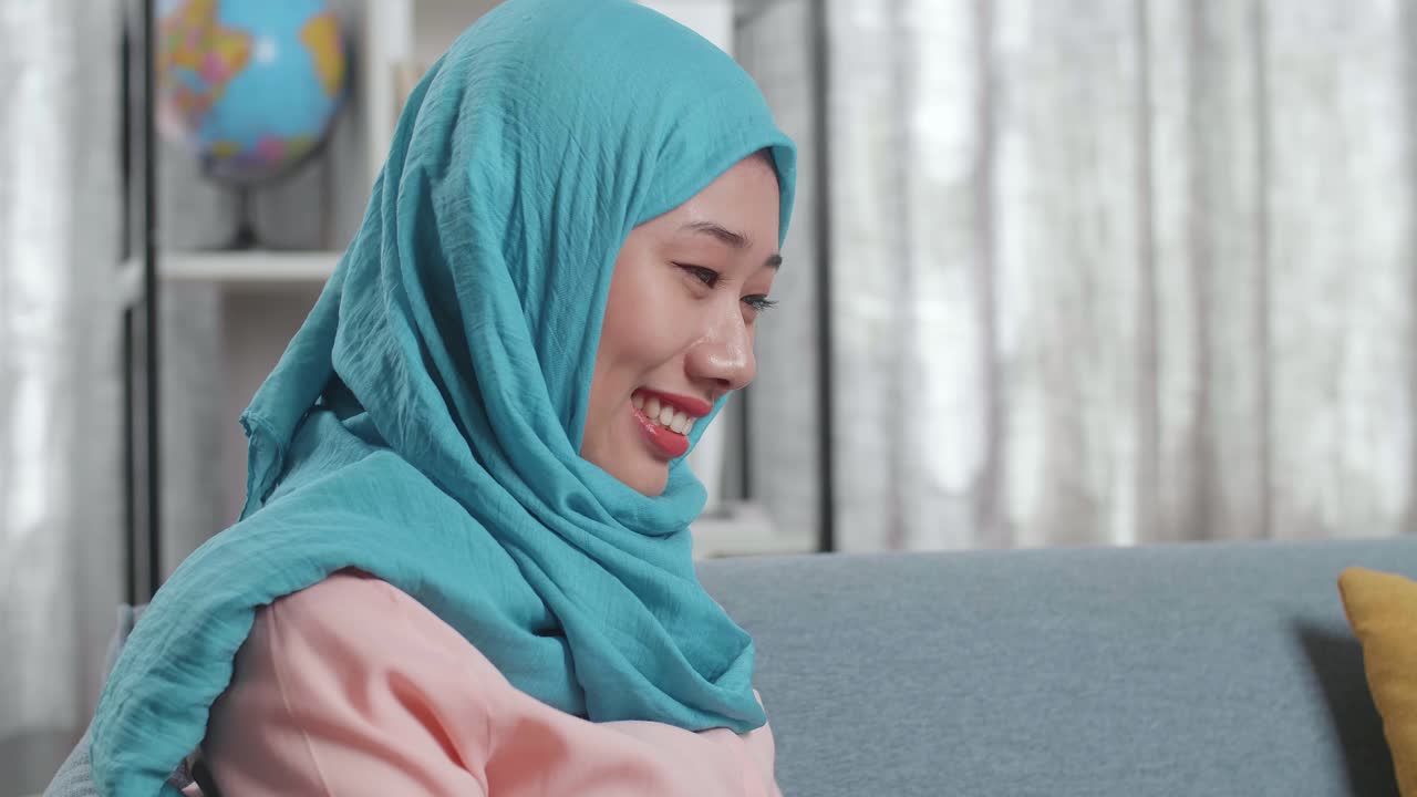 히자브를 입은 미소 짓는 여성이 엄지손가락을 올리고 있습니다.