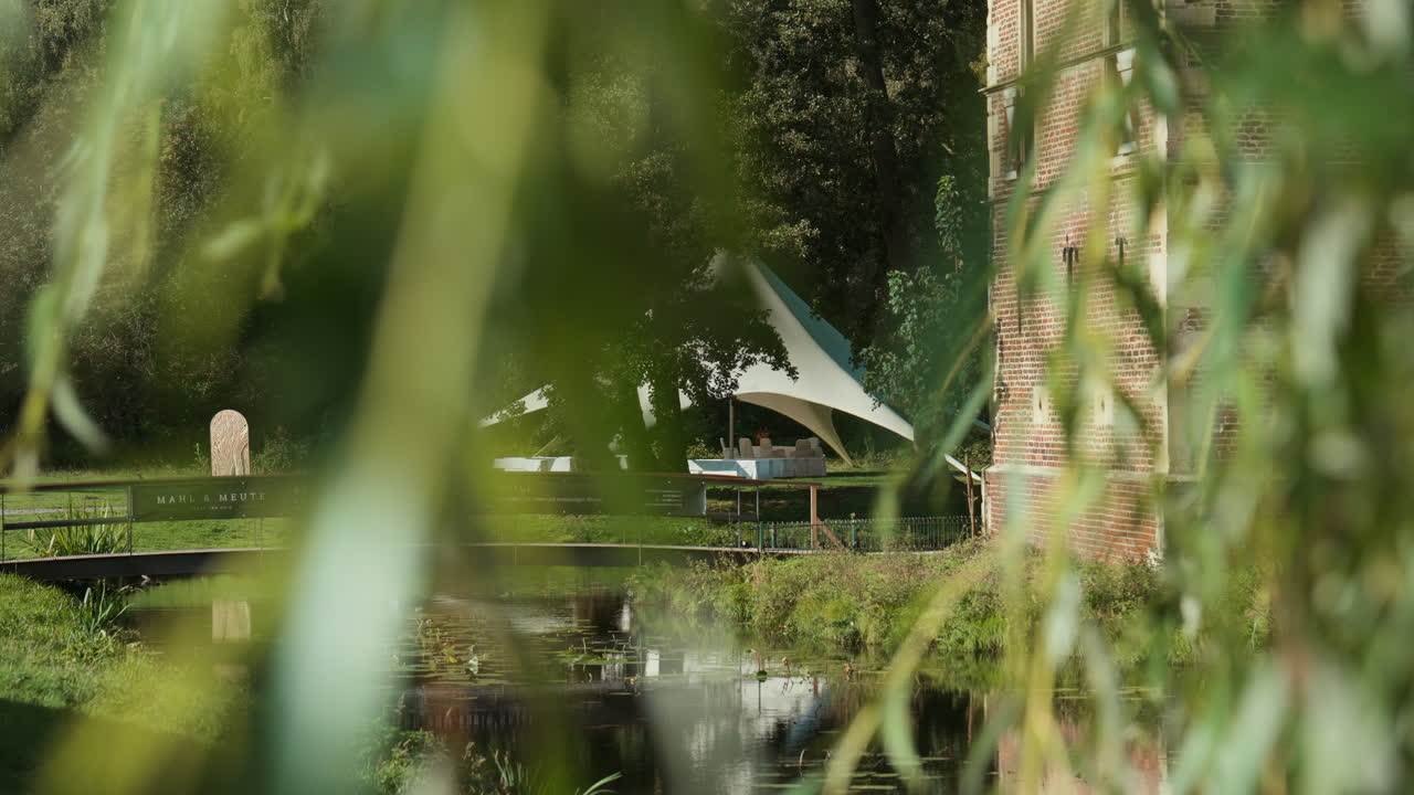 Scenic wedding ceremony spot by a river, surrounded by lush trees and greenery. A nearby castle adds charm and elegance, making this a perfect outdoor venue for romantic celebrations