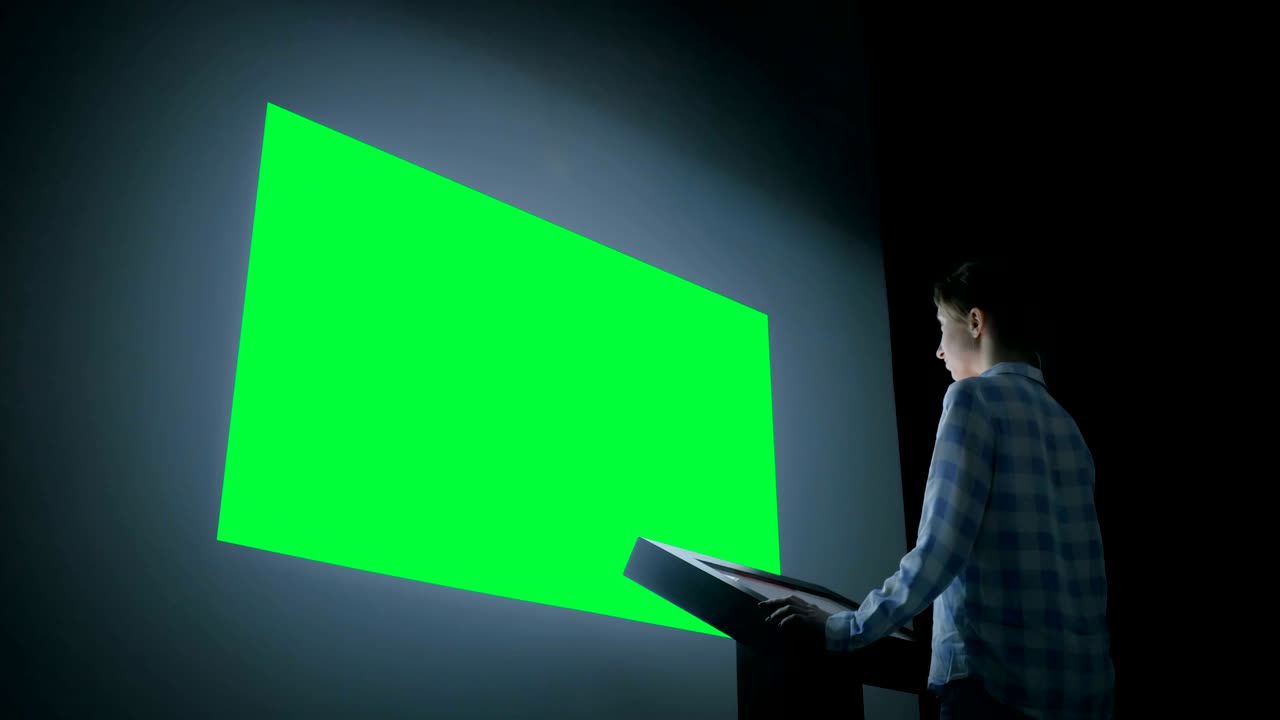 Woman looking at blank large interactive wall display - green screen concept