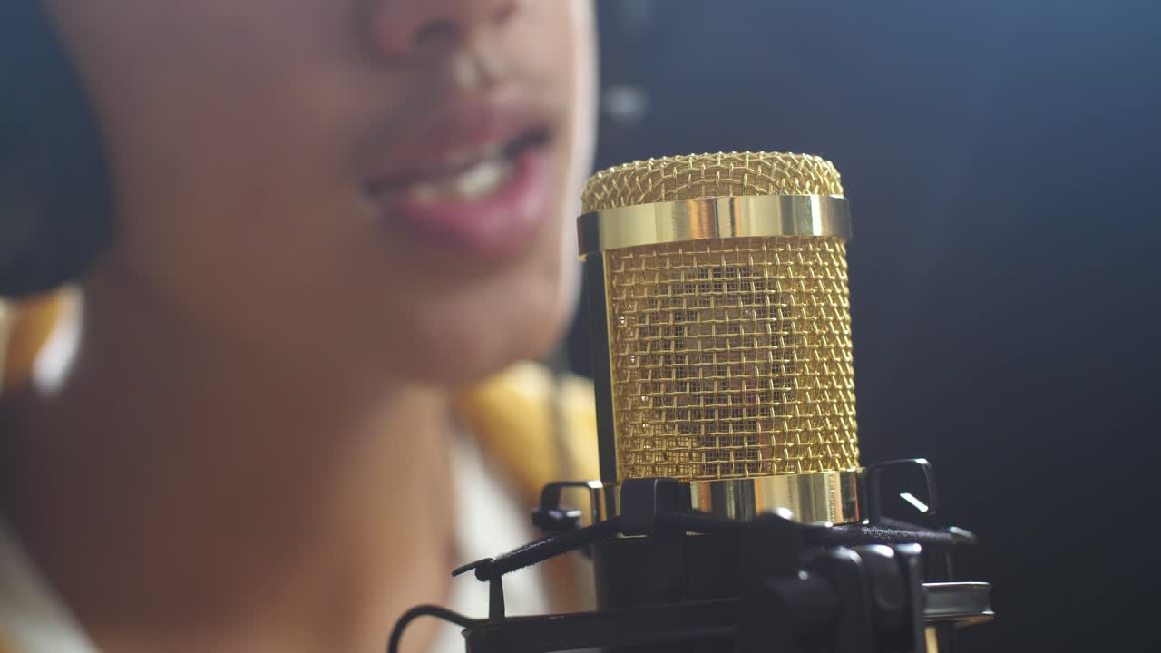 cerca de un micrófono de condensador que está siendo utilizado por un joven cantante en el fondo negro