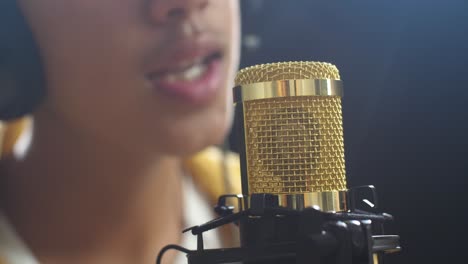 close up of a condenser microphone being used by a young boy singer on the black background