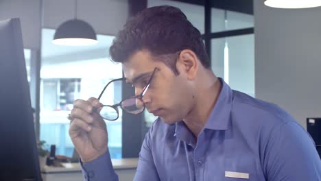 stressed out, overburdened and tired out young male staff member sitting in front of a computer