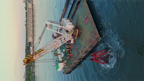 vertical aerial view of grab dredger on pontoon excavating sediment from river