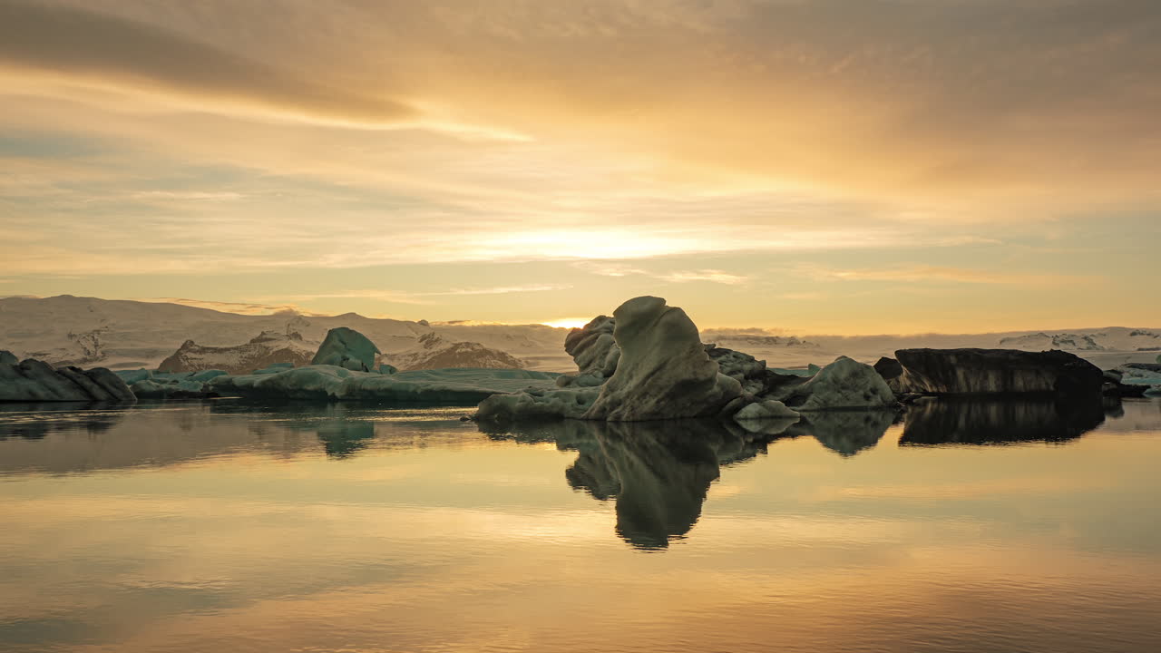 Ohnivý západ slunce nad ledovcovou lagunou Jökulsárlón na jihu Islandu s odrazem na vodě. - statický záběr - časosběr.