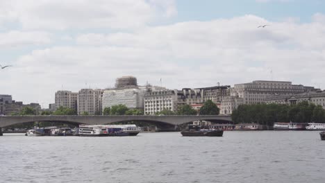 waterloo bridge in london over thames river with few boats, nice weather, wide angle static view