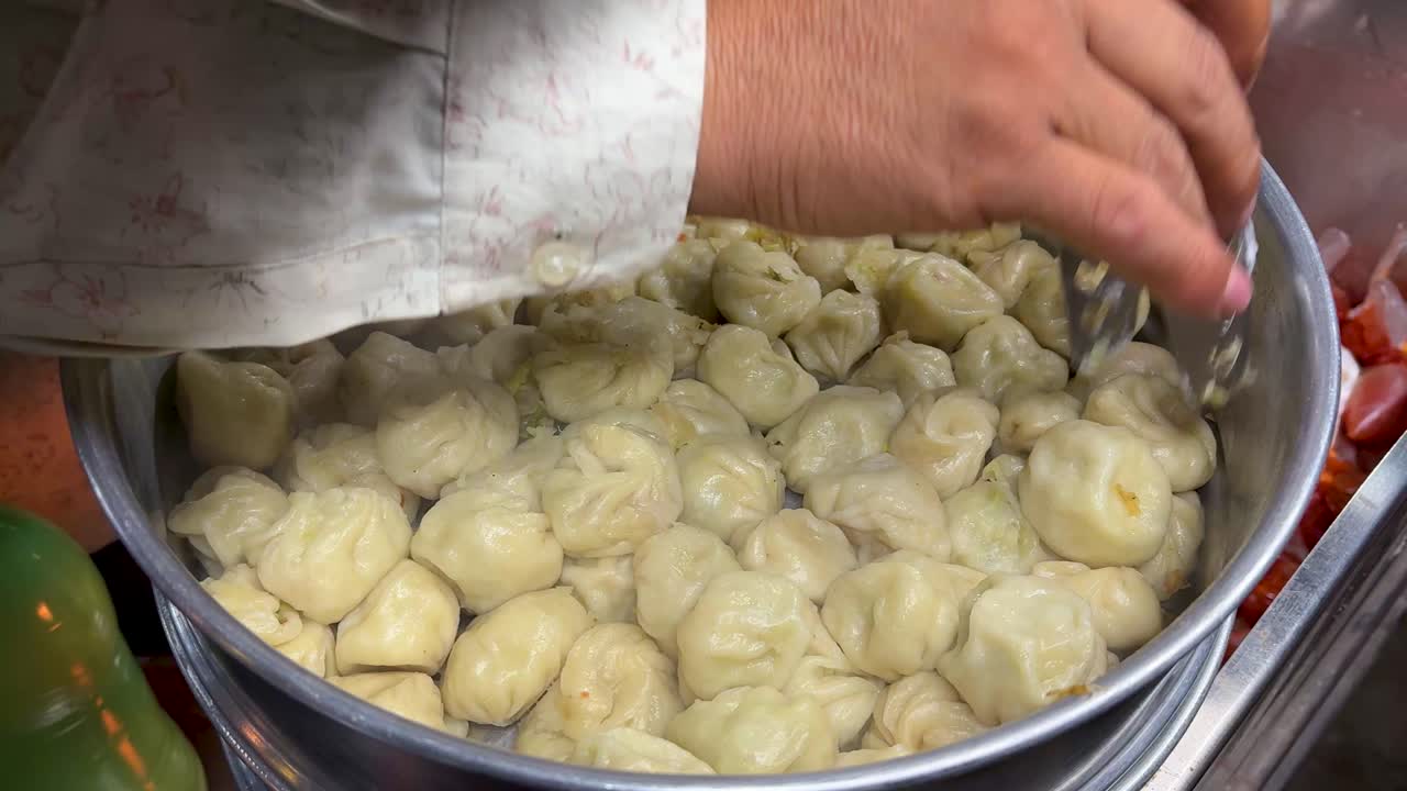 음식 판매대에서 손으로 뜨겁게 찐 만두를 제공하는 모습 클로즈업