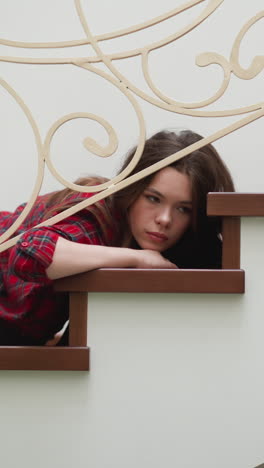 woman with depressive mood lies on stairs. exhausted lady loses will to do routine tasks in cause for emotional burnout at home. pensive woman expression