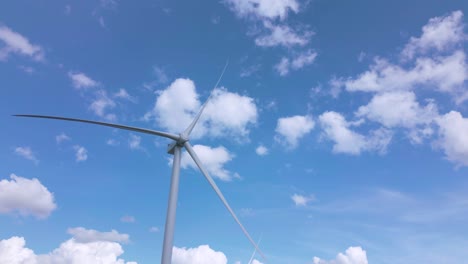 aerial tilt up revealing motionless wind turbines on sunny day