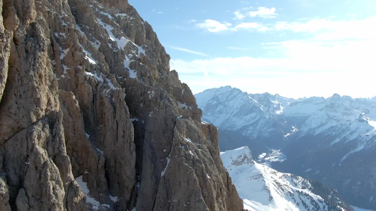 toma ascendente de la montaña rocosa fassa con una cordillera cubierta de nieve en el fondo a la luz del sol