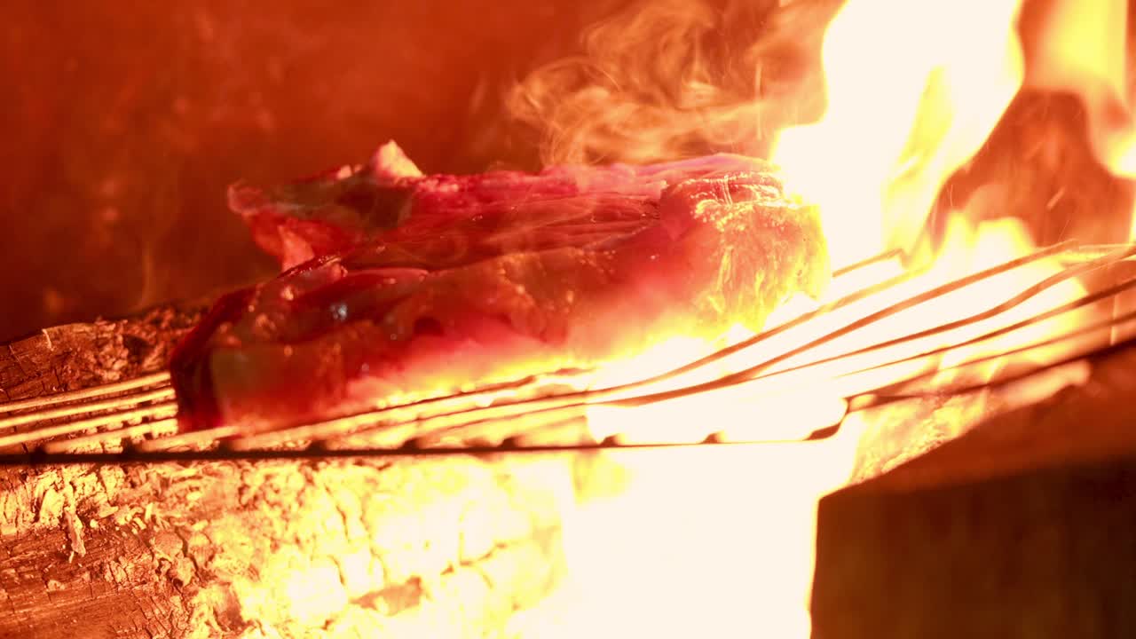 Beef steak cooking on the grill over the fire.