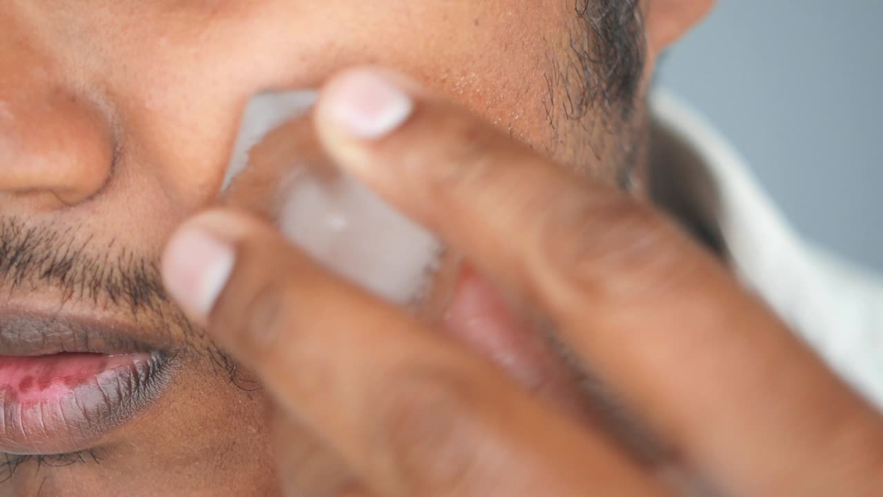 Uomo che applica ghiaccio sul viso per la cura della pelle