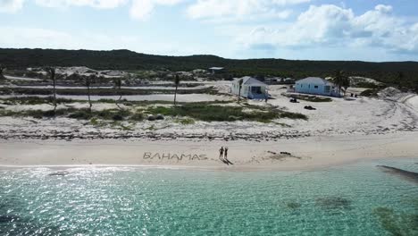 aerial view of a couple drawing the word "bahamas" on the beach