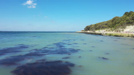 aerial shot over blue sea water, starting low then rising, shot on a blue sky day