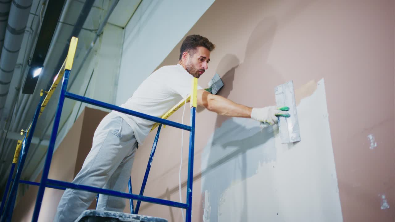 A Skilled Painter Working on a Wall Restoration Project Using a Trowel from a Sturdy Scaffold, Ensuring a Smooth Surface for Upcoming Finishing Touches