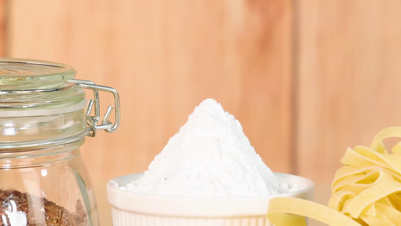 A variety of grains, pasta, and bread arranged on a wooden surface with natural lighting