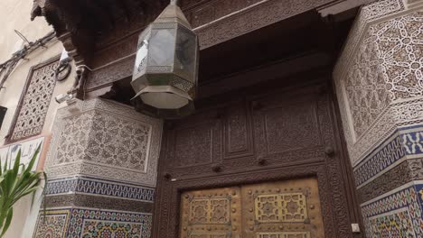 Downward-panning-view-of-ornate-doorway-and-lamp-in-Marrakesh,-Morocco