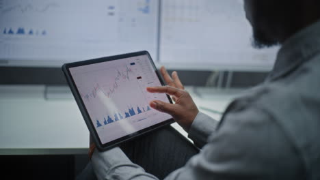 stock exchange trader in wireless headphones having call, monitoring real-time stocks, exchange market charts on multi-monitor desk setup. african american investment agent working. vertical shot.