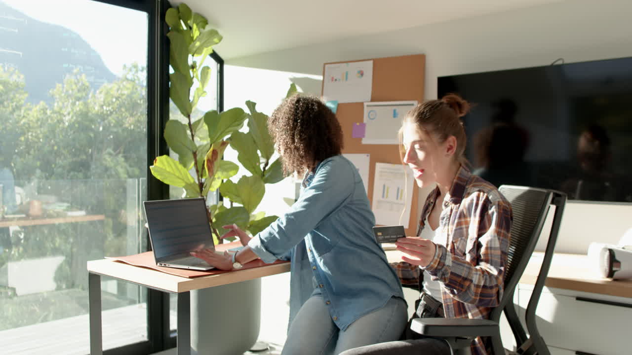 Using laptop and holding credit card, women shopping online at home office