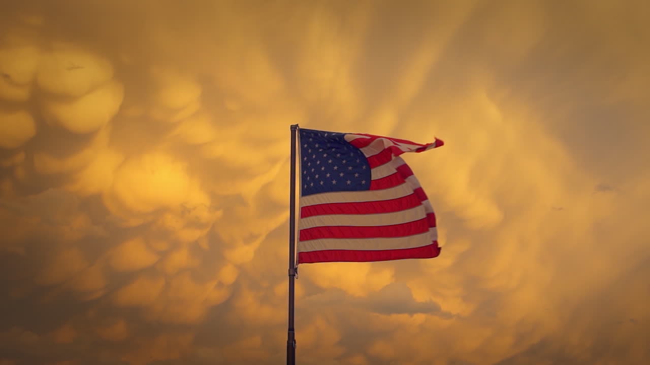 United States Flag flying against large orange Mammatus storm clouds.