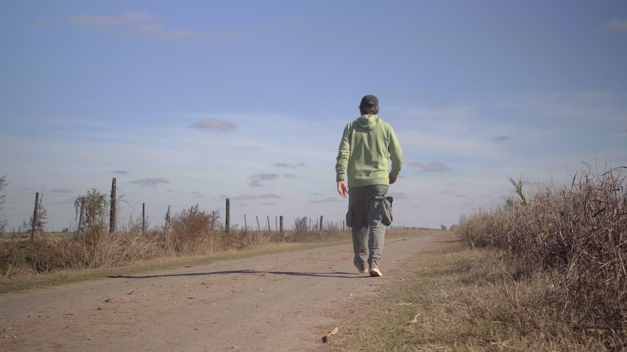 시골 환경 의  도로 를 가로질러 카메라 에서 멀리 걸어가는 사람 의 뒤쪽 모습