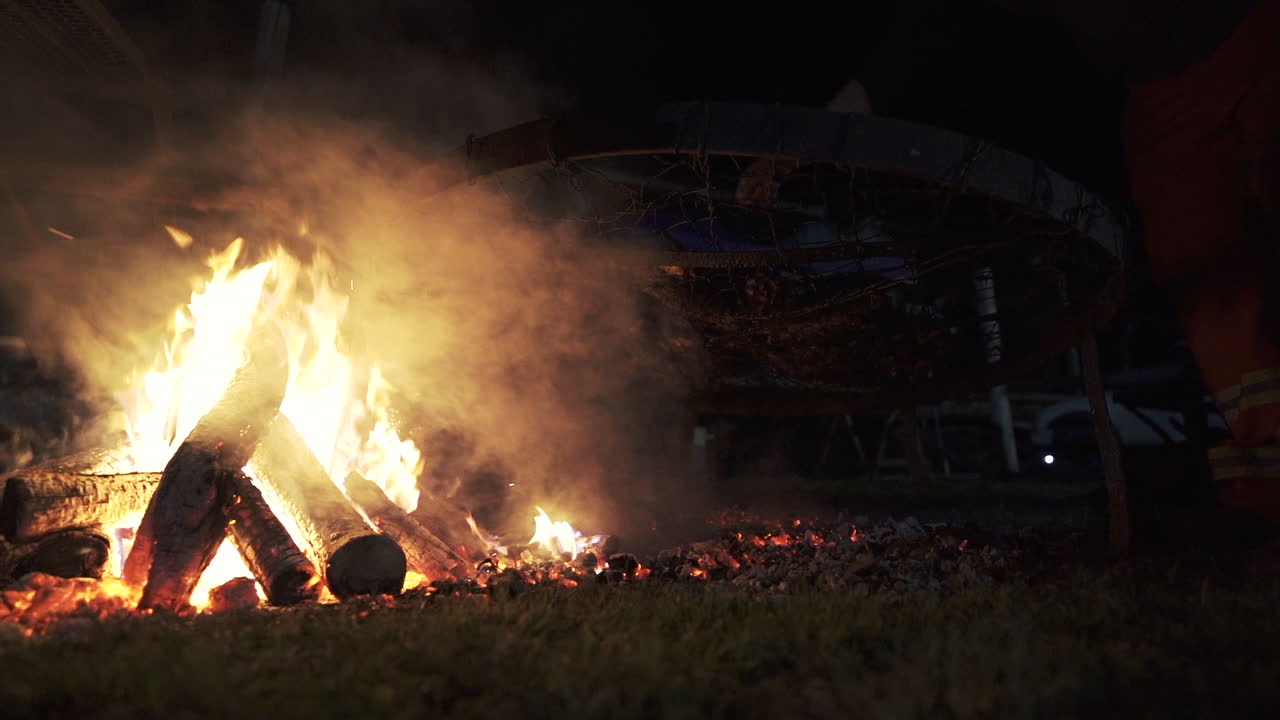 gran fuego de leña asando carnes por la noche durante un asado argentino - cámara lenta