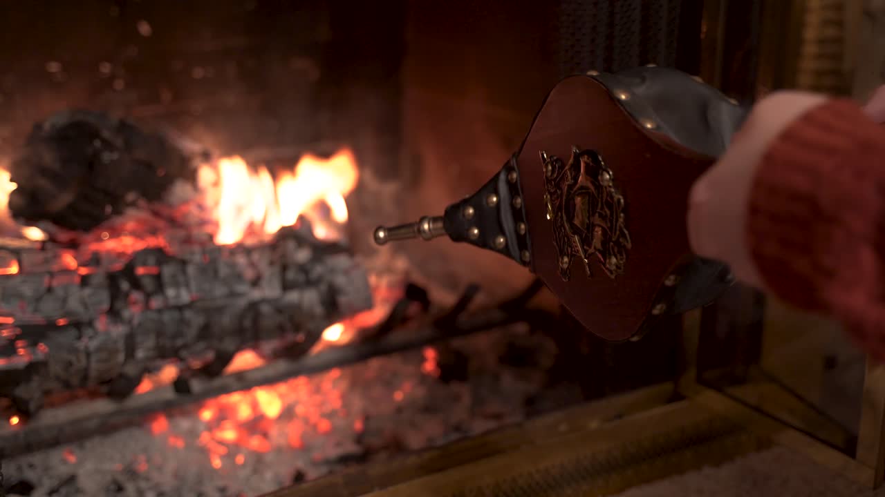 벽난로 풀무로 불을 피우는 여자