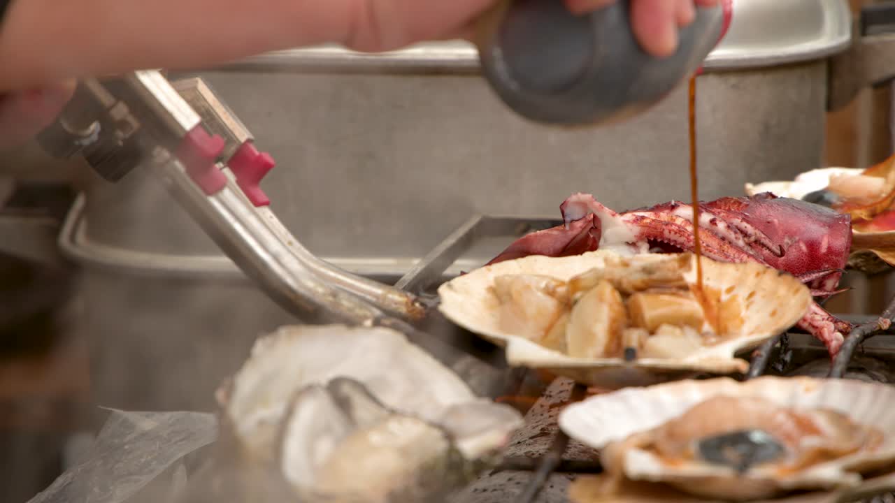Close-up of a vendor searing fresh scallops and oysters with a blowtorch in Tokyo