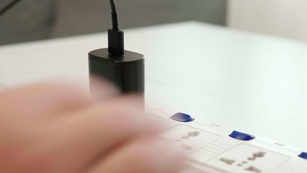 mano del hombre enchufando el cargador de batería del adaptador de teléfono y encendiendo el interruptor para usar un teléfono móvil