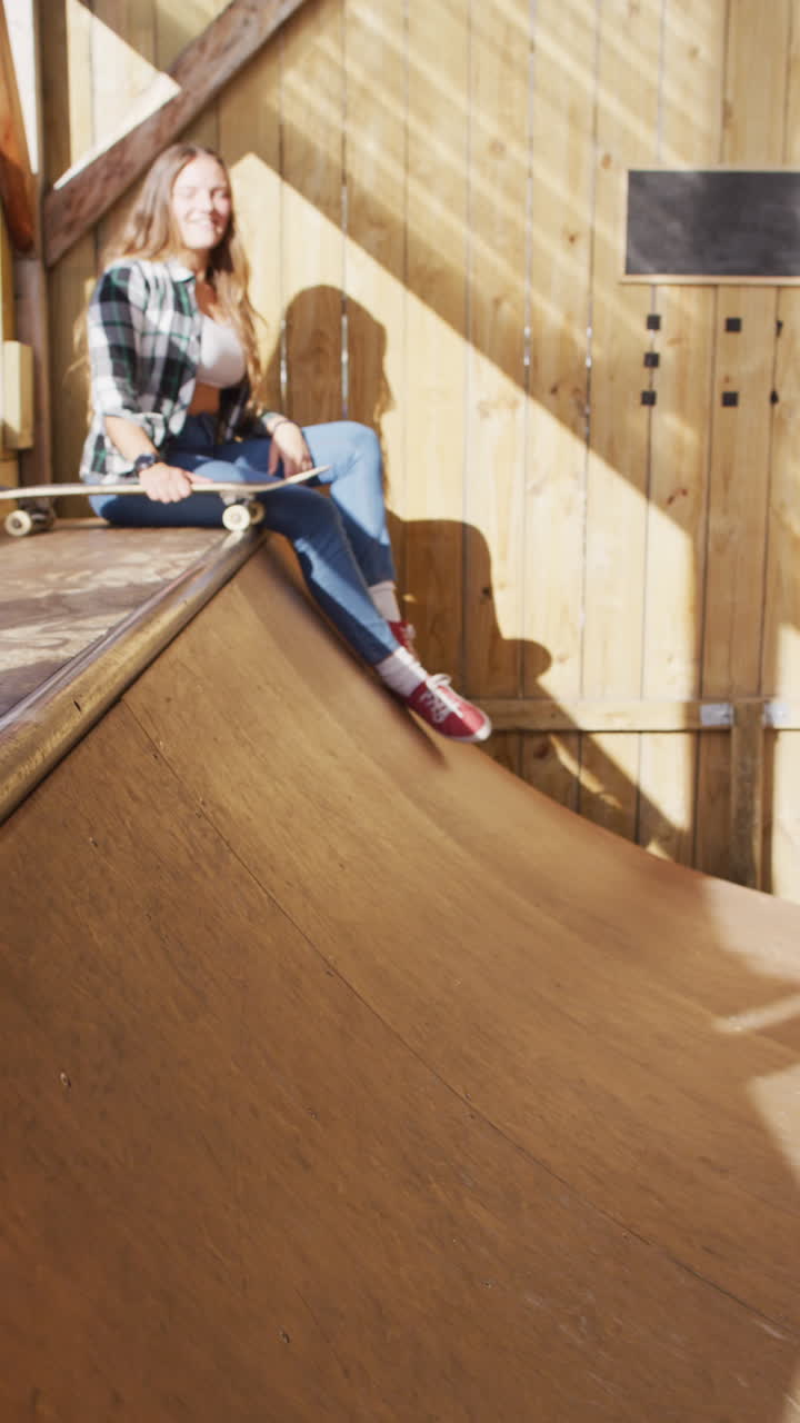 Vertikal video af kaukasiske kvindelige og mandlige skateboardere i skatepark.