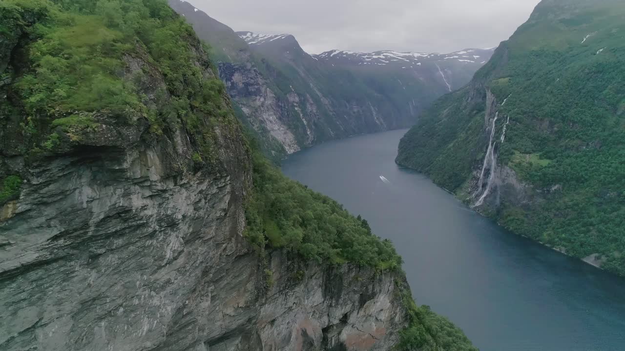 slomo aéreo do fiorde de geiranger, noruega, voando para frente com um barco em movimento ao fundo, passando pelas sete irmãs