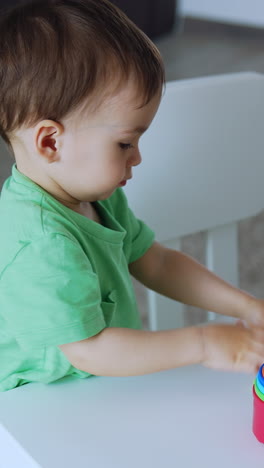 charming baby playing with bright toys at the desk. caucasian toddler is busy with toys at playroom. vertical video