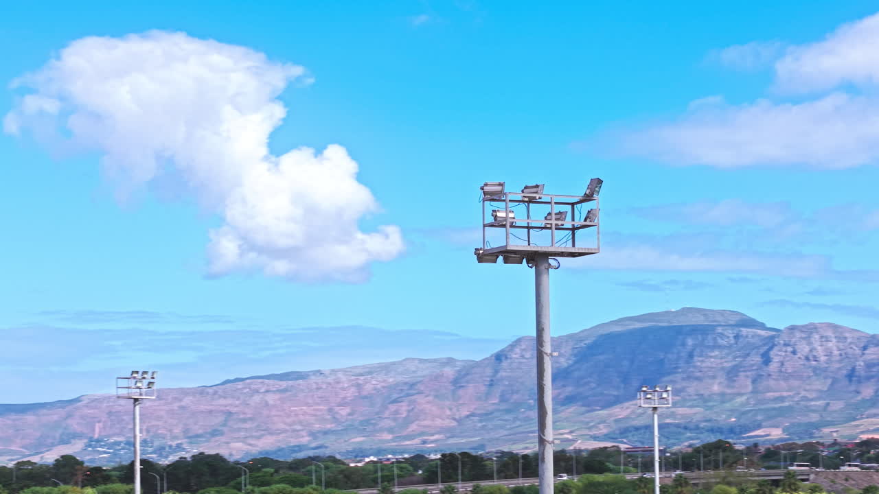 Fari di un campo sportivo sullo sfondo di cieli blu e montagne