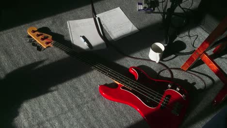 slow zoom down into burnt orange electric bass guitar and songwriting materials sitting on the floor in the morning sun